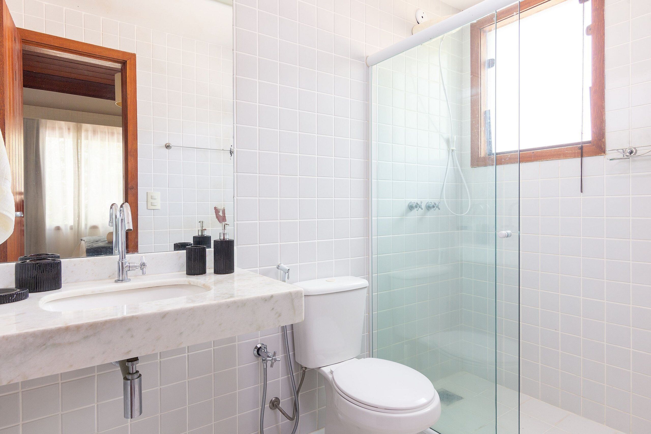 A bathroom with a white sink, mirror, toilet, and glass shower enclosure.