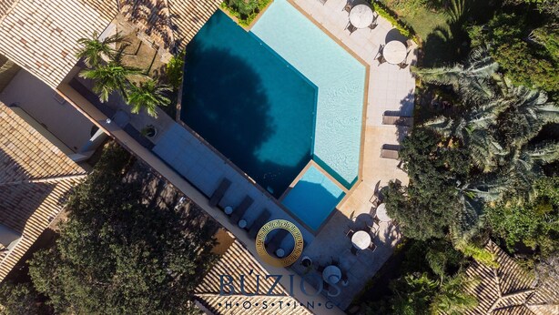Vista aérea de un resort con piscina, tumbonas y palmeras.