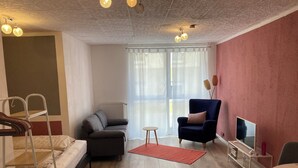 Una sala de estar moderna con sofá, sillón y mueble para televisión.