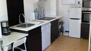 Una cocina compacta equipada con lavavajillas, pileta, cafetera y microondas.