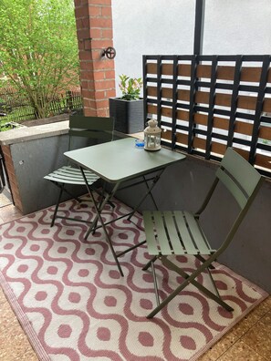 Un espace patio aménagé avec une table et des chaises, une lanterne et une plante en pot.