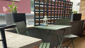 Un patio con una mesa, sillas, un muro de ladrillo y una alfombra estampada.