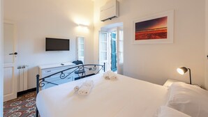 A bedroom with a bed, a bedside lamp, a TV mounted on the wall, and a painting.