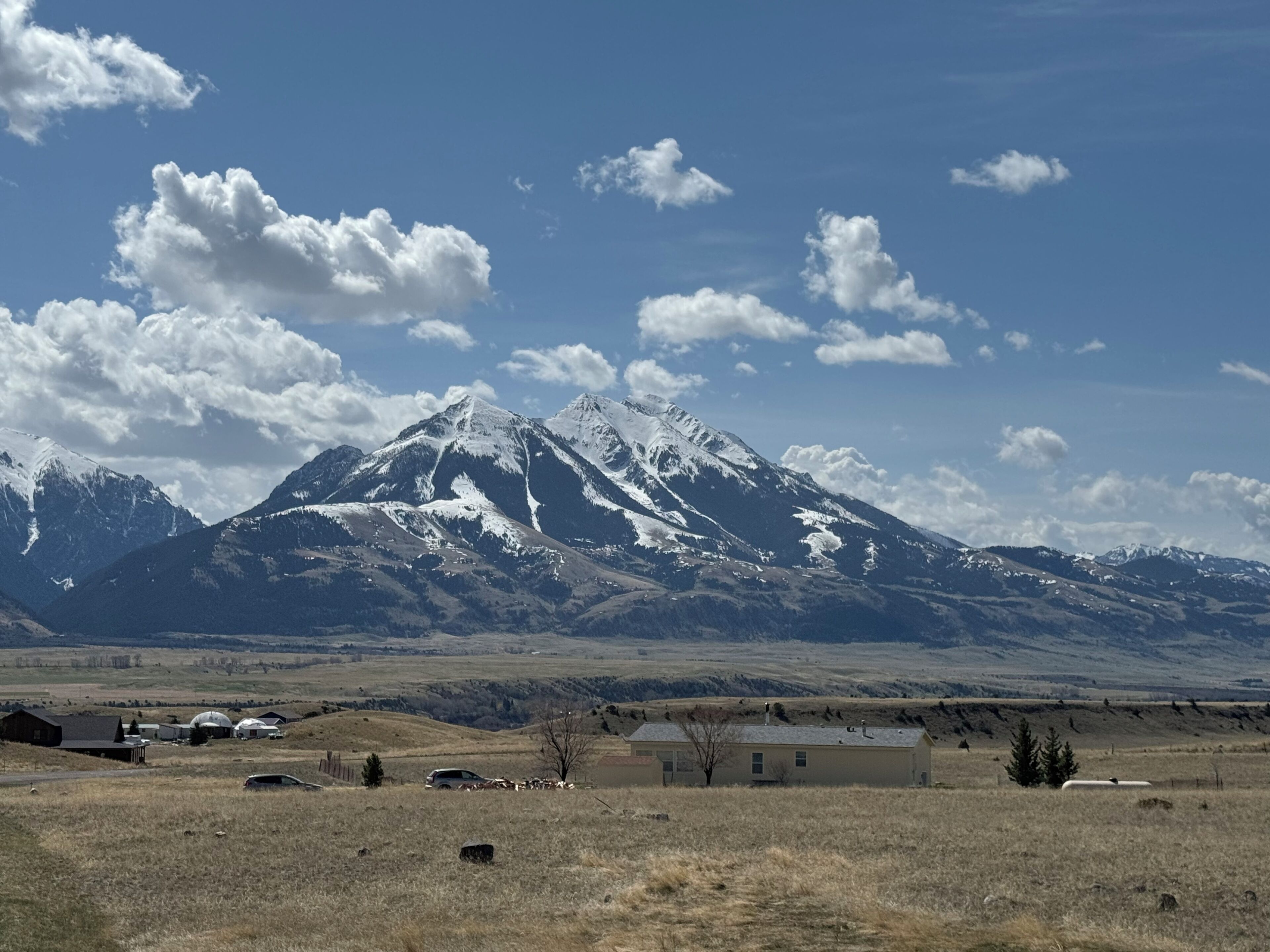 Un paysage de montagne avec une maison située dans un champ.