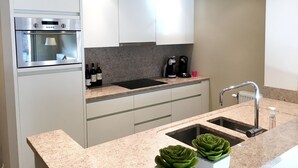 A modern kitchen with a built-in oven, a coffee maker, and a sink. - Apartment in Knokke Near Beach and Casino (Knokke-Heist)