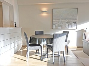 A dining area with a round table, four chairs, a white cabinet, and a painting on the wall.