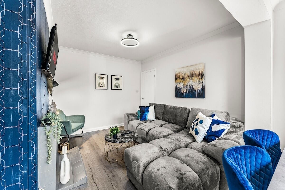 A modern living room with a sectional sofa, a coffee table, and a TV mounted on the wall.