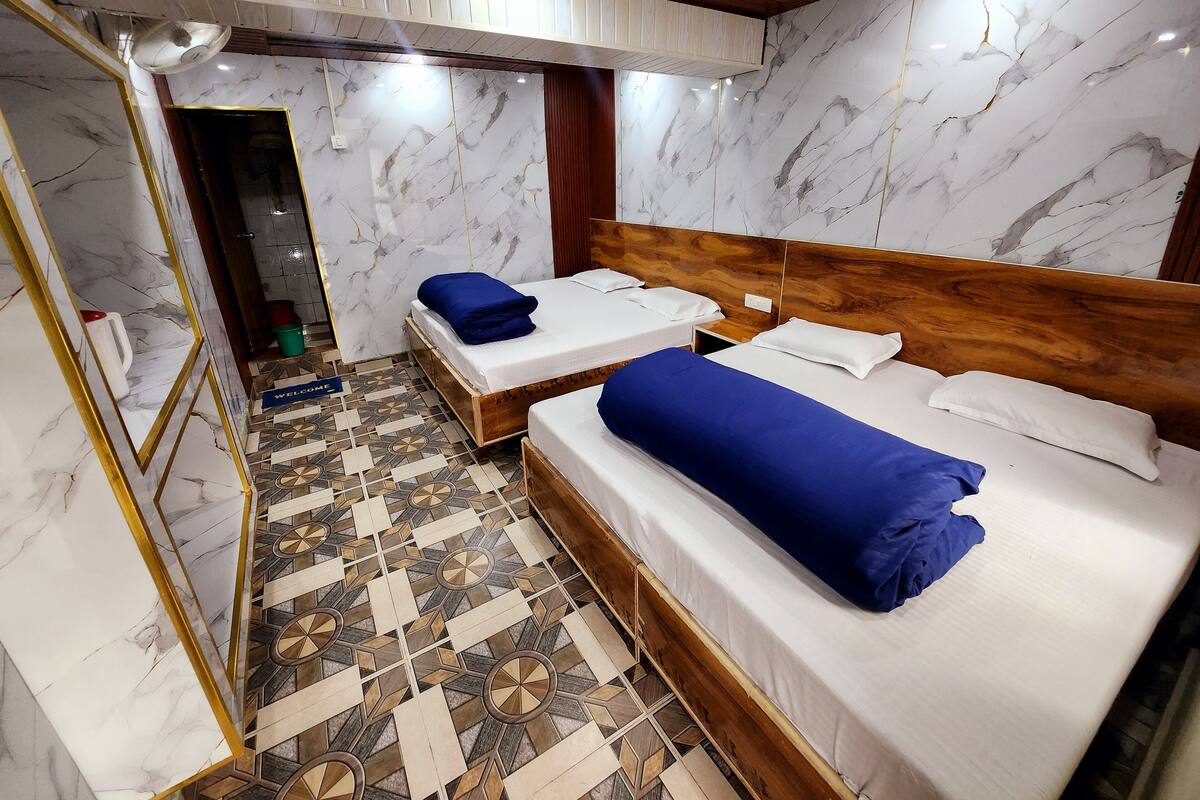 A hotel room with two beds, marble walls, a wooden headboard, and a patterned floor.
