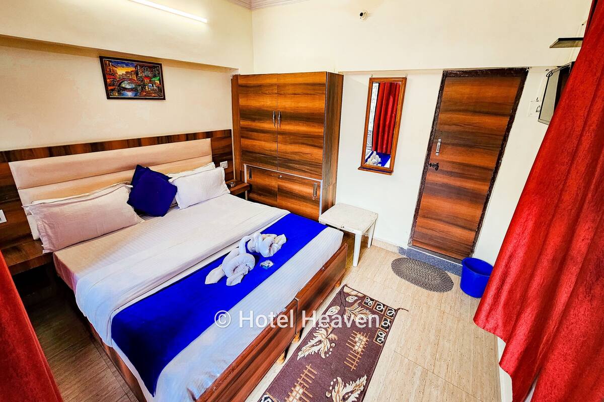 A hotel room with a bed, wardrobe, and a painting on the wall.