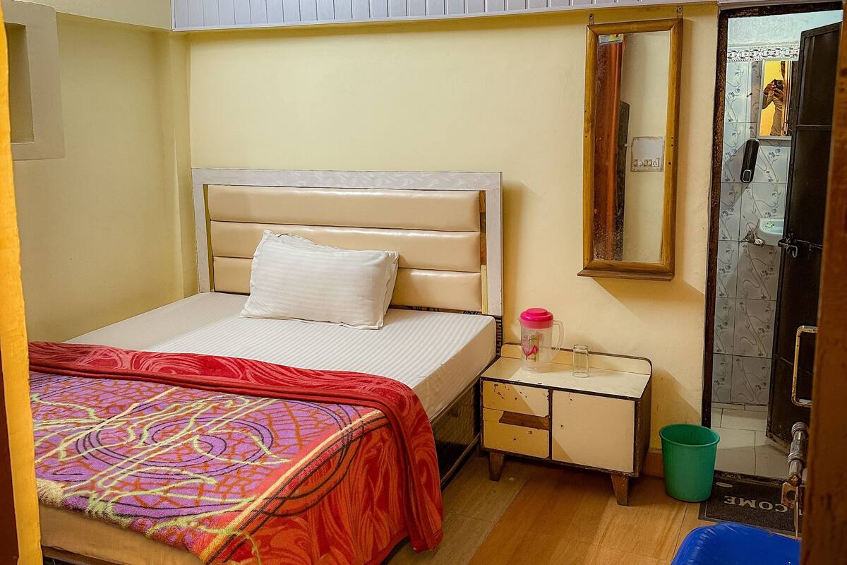 A bedroom with a bed, bedside table, and a mirror.