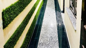 Un pasillo con paredes de césped artificial verde, suelo de mármol y techo decorativo.