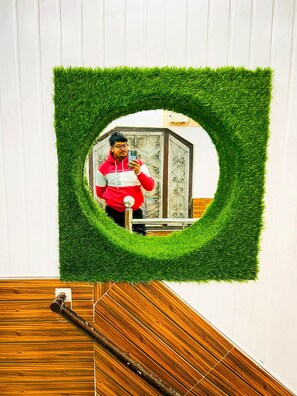 A mirror framed with artificial grass, a wooden staircase, and a metal railing. - Hotel Heaven  (Chamoli)