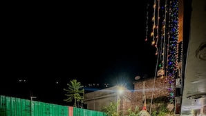 Un patio con suelo verde y blanco, mobiliario exterior e iluminación con luces colgantes.
