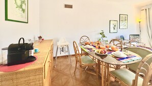 Un comedor con una mesa redonda, sillas y una zona de bar con un bolso negro y un vaso.