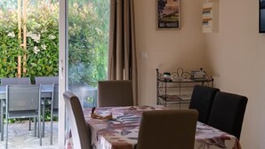 Ein Essbereich mit Tisch, Stühlen, einem Deckenventilator und Blick ins Grüne.