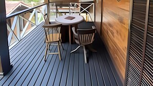 A wooden deck with a table and chairs, a railing, and a view of greenery. - Linda casa na Praia de Cambury - SP - 4  (Sao Sebastiao)