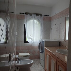A bathroom with a toilet, bidet, washing machine, and a sink. - Belvedere Apartment Ac Budoni (Budoni)