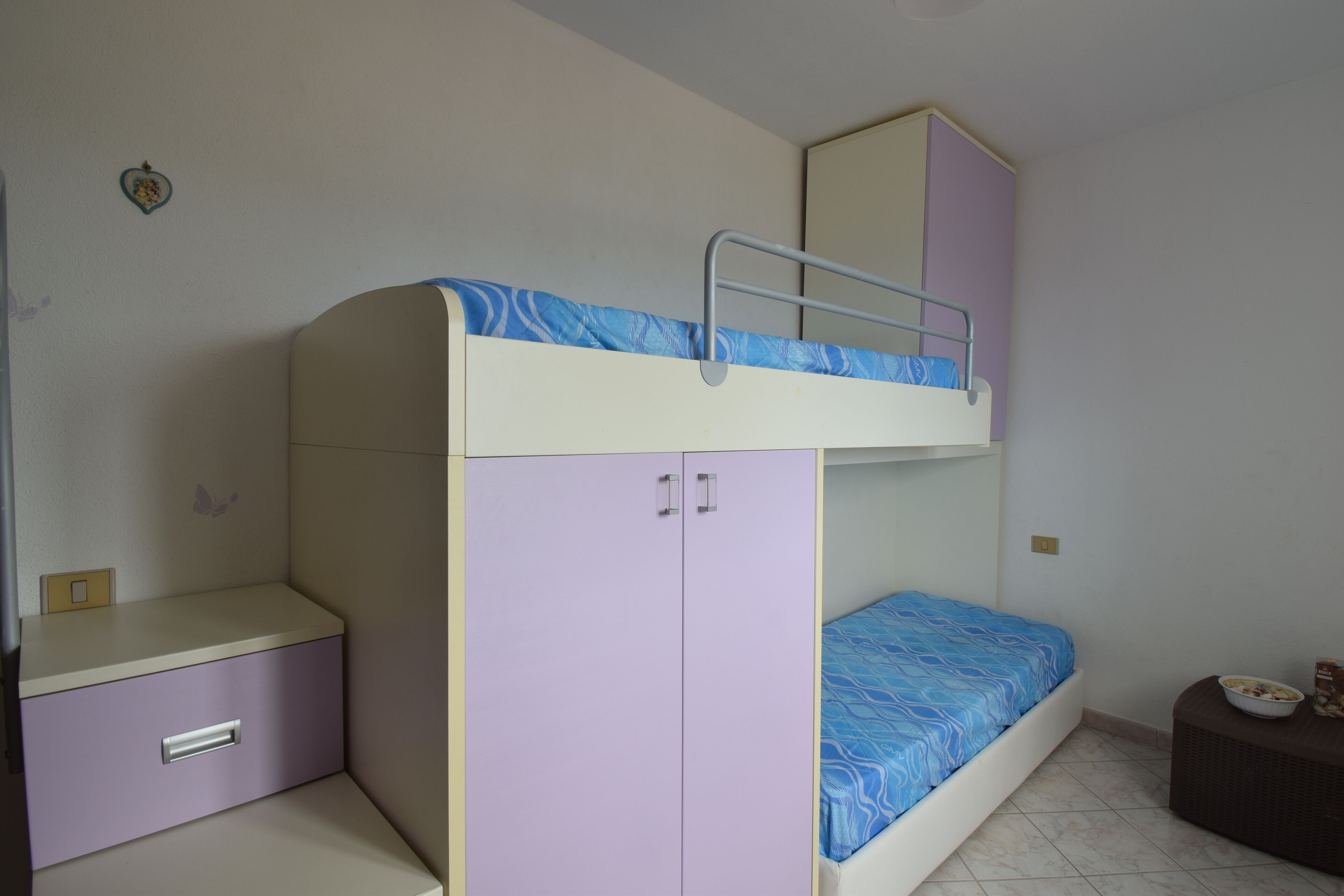 Ein Etagenbett mit Schreibtisch und Kleiderschrank, ein Spiegel und ein kleiner Tisch mit einer Schüssel.