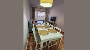 A dining area with a white table and chairs, a vase with flowers, and a television on the wall. - Sea View - Ground Floor - Pool - Beachaccess (Vera)