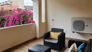 A balcony with wicker furniture, a small table, and an air conditioning unit. - Sea View - Ground Floor - Pool - Beachaccess (Vera)