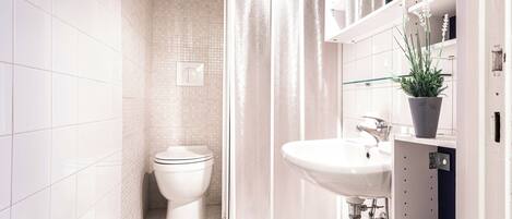 A modern bathroom with a toilet, shower, and sink.