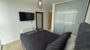 Een slaapkamer met een bed, een televisie, een spiegel en een schuifpui.