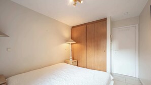 A bedroom with a bed, a nightstand, a lamp, a wardrobe, and a door. - Apartment in Knokke-heist With Sea Views (Knokke-Heist)