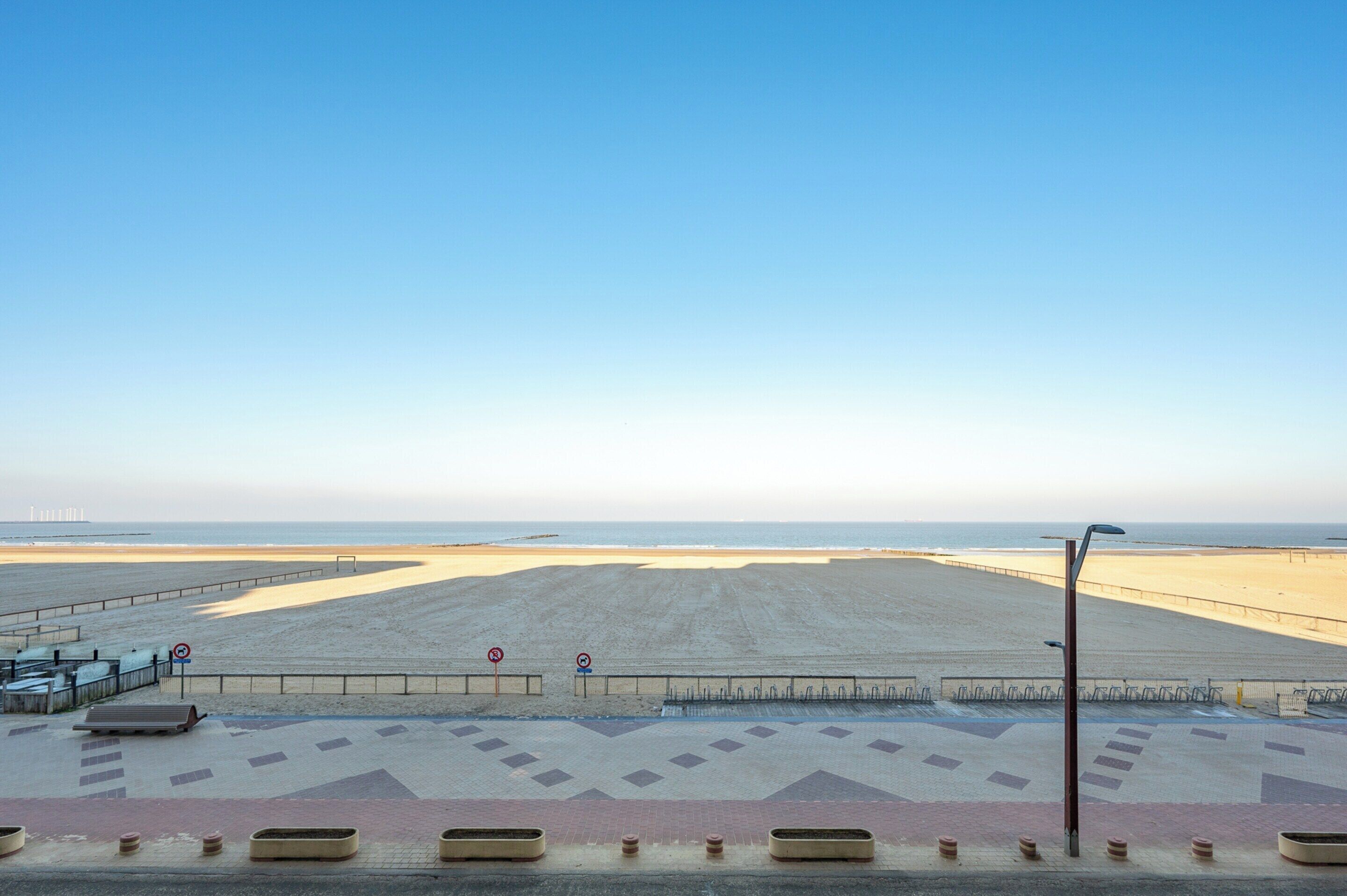 Uma praia com calçada, bancos e guarda-corpo.