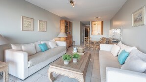A modern living room with two sofas, a coffee table, and a dining area with a table and chairs. - Apartment in Knokke-heist With Sea Views (Knokke-Heist)