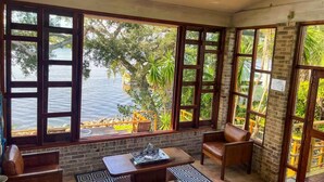 A room with large windows, a brick wall, and a view of a body of water. - Pellicanus House. Waterfront Paradise+Pool+Hot Tub+ Kayaks Adventure! (Palm Bay)