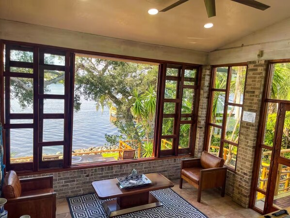 A room with large windows, a brick wall, and a view of a body of water.