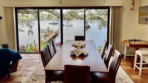 A dining area with a view of a lake, a ceiling fan, and a chessboard. - Pellicanus House. Waterfront Paradise+Pool+Hot Tub+ Kayaks Adventure! (Palm Bay)
