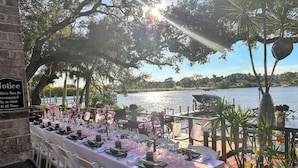 A table set for a formal outdoor event with a view of a lake and boats. - Pellicanus House. Waterfront Paradise+Pool+Hot Tub+ Kayaks Adventure! (Palm Bay)