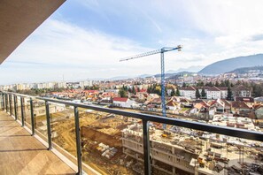 A balcony with a view of a cityscape, including residential buildings and a construction site. - MoHost Penthous and MoHost View (Brasov)