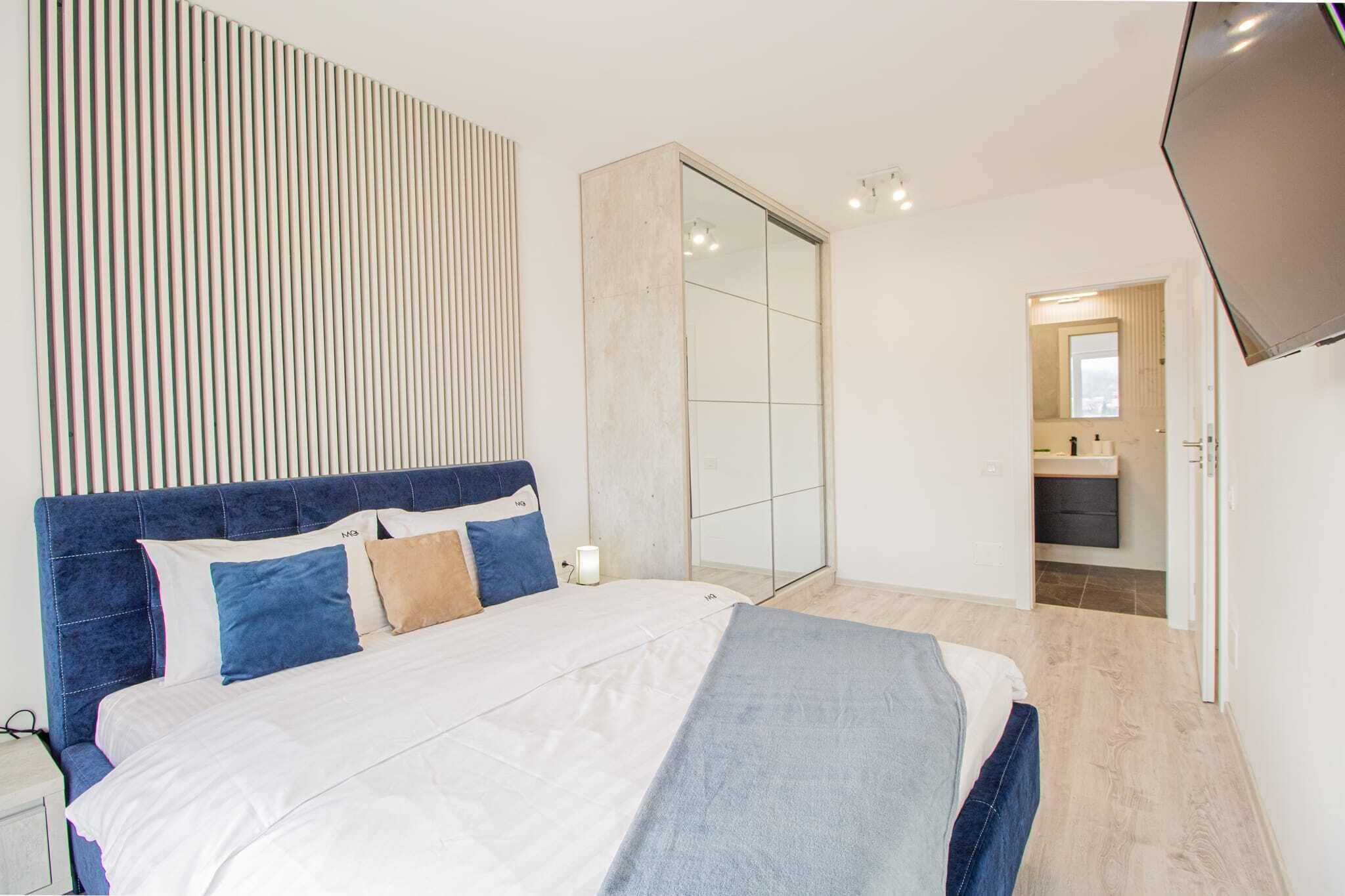 Un dormitorio moderno con una cama grande, un armario y un televisor.