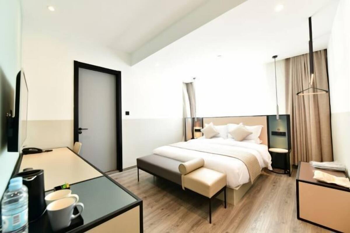 Una habitación de hotel moderna con cama, mesitas de noche, escritorio y televisor.