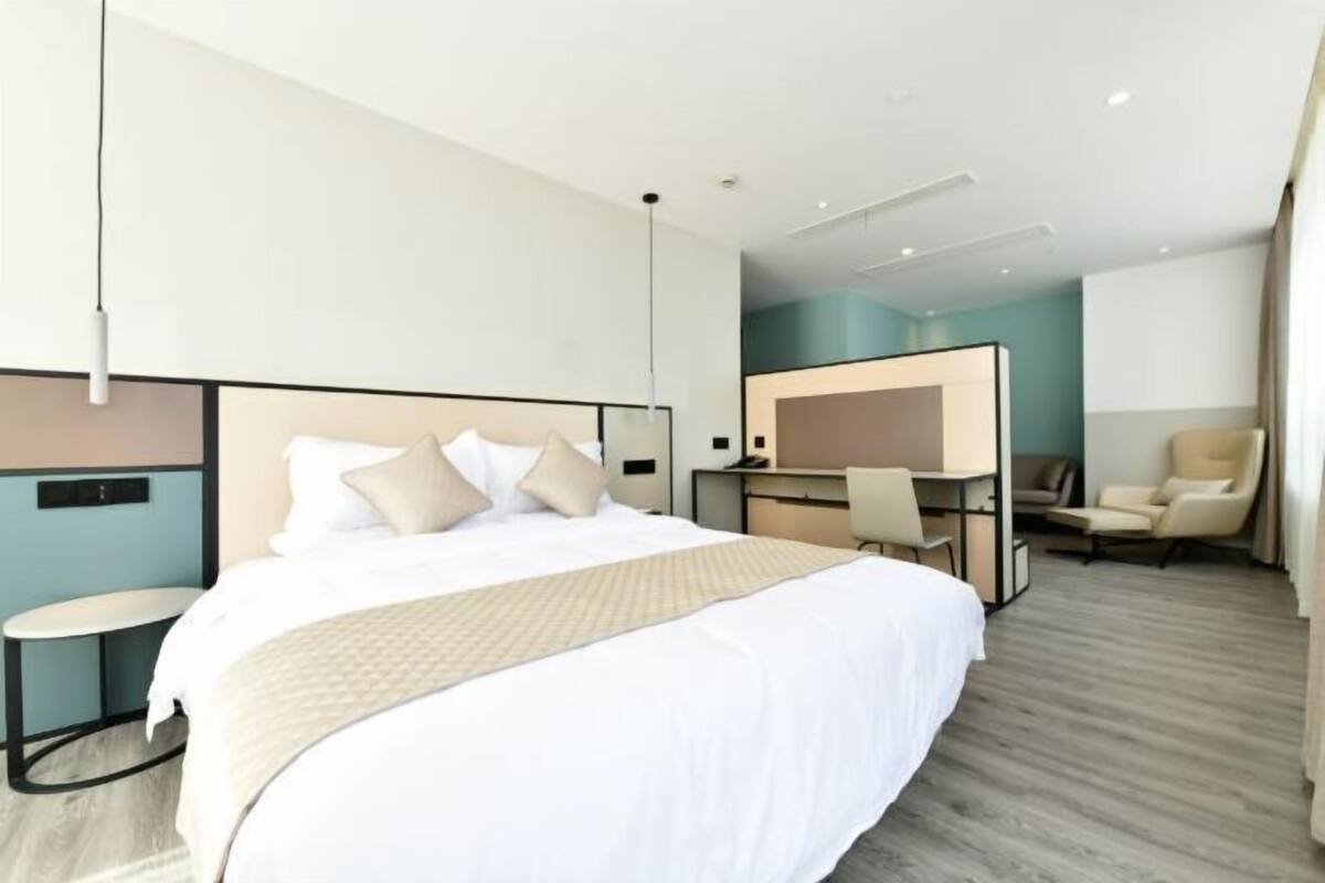 Una habitación de hotel moderna con una cama grande, un escritorio y una silla.