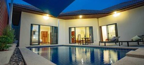Ein moderner Poolbereich mit klarem Pool, Schiebegläsern und einer Sitzgruppe mit Tisch und Stühlen.