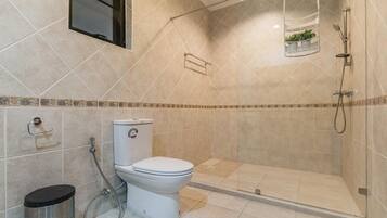 A modern bathroom with a toilet, shower, and a small window above the toilet.
