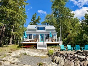 A house with a deck, outdoor seating, and a stone wall.