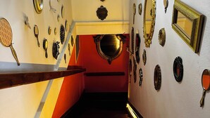 Una escalera con espejos ornamentados y apliques en la pared, que conduce a un nivel inferior.