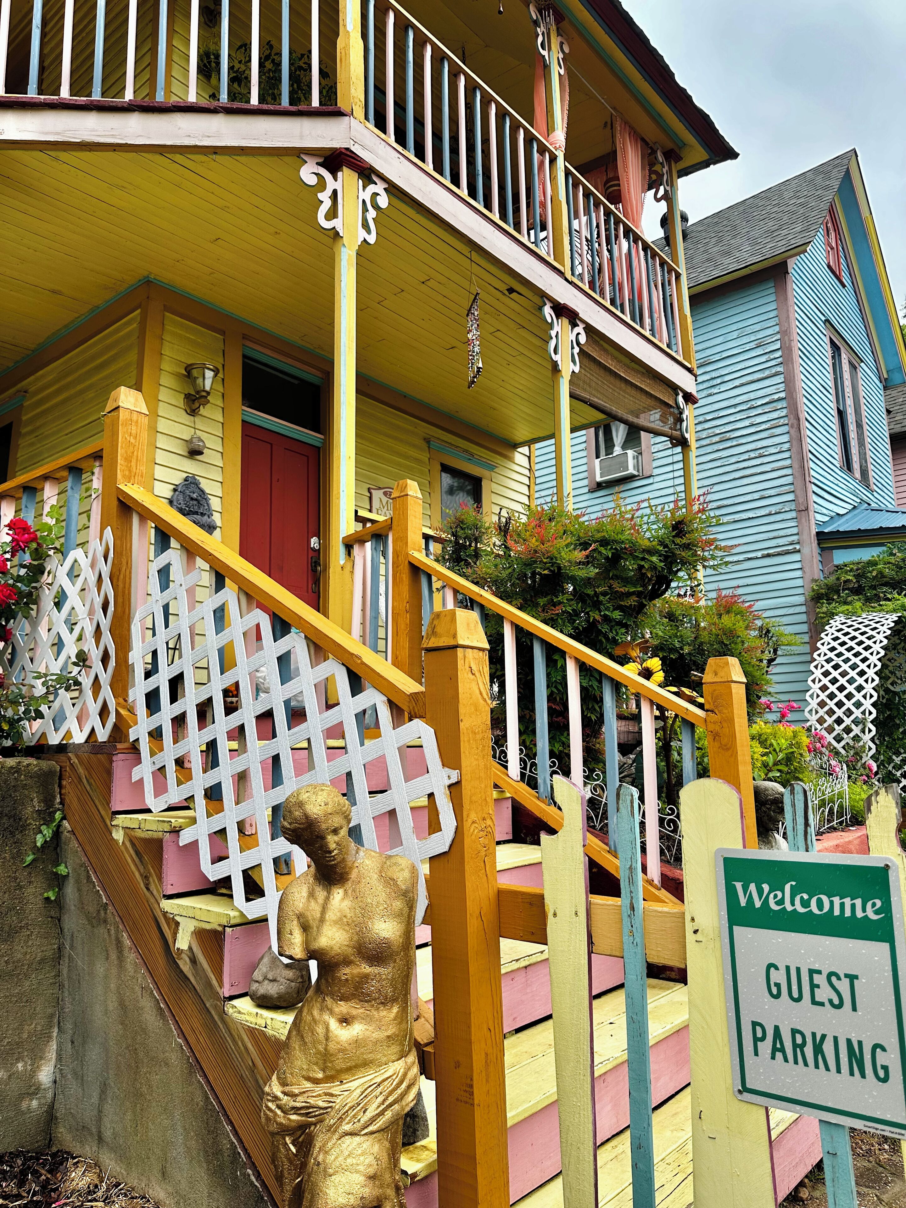 Une maison aux couleurs vives, dotée d’un porche, d’un escalier et d’un panneau indiquant « Parking réservé aux invités ».