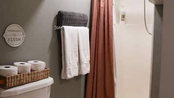 A bathroom with a toilet, a shower, and a towel rack.