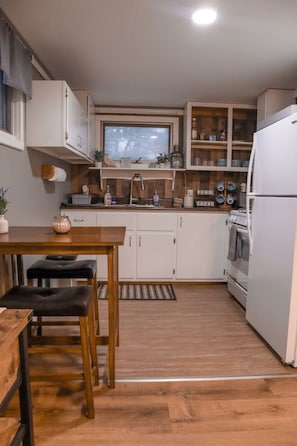 Eine kompakte Küche mit weißen Schränken, einem Holztisch und einem eingebauten Backofen.