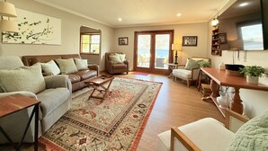 A living room with a sofa, armchair, coffee table, and a rug. - Modern Lakeside Home (Glenburn)
