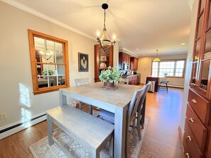 A dining area with a wooden table, benches, and a chandelier.