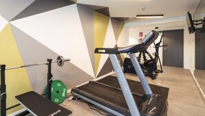 A gym with a treadmill, weight bench, and weight plates. - Casa Rosada (Mar del Plata)