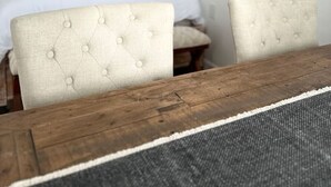 Un dormitorio con una cama, dos sillones tapizados, una mesa de madera, una lámpara colgante y un estante con una planta.
