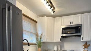 Una cocina moderna con armarios blancos, electrodomésticos de acero inoxidable y suelo de madera.