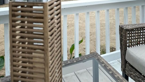 Una terraza con mobiliario de mimbre que da a un área verde con vista al lago.